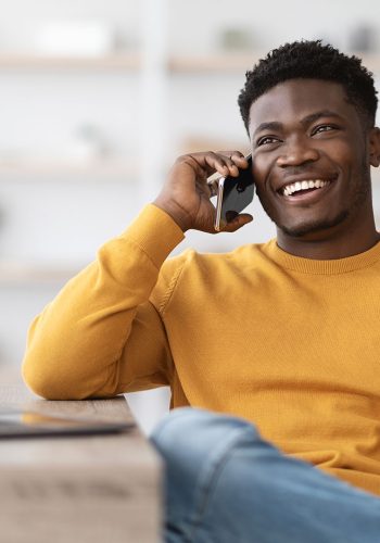 Homem sorrindo usando celular em casa com internet fibra óptica Log-Fi